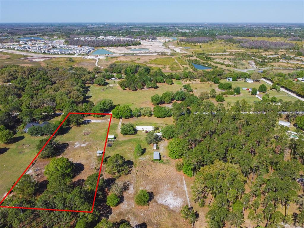 An aerial view shows a rectangular plot of land outlined in red amidst rural terrain — TINA MARIE DRIVE, ZEPHYRHILLS, FL