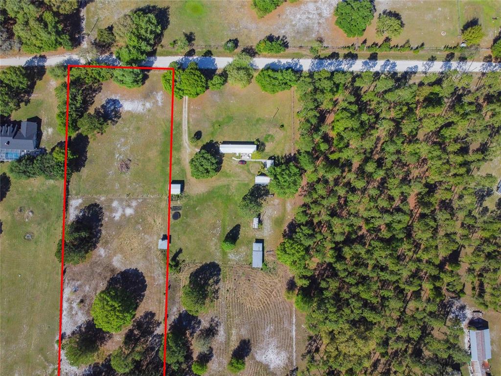 An aerial view shows a rural property with a house, outbuildings, and wooded areas — TINA MARIE DRIVE, ZEPHYRHILLS, FL