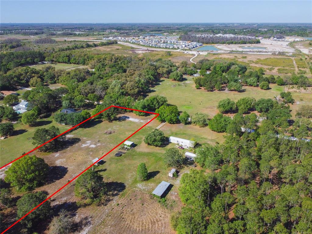 An aerial view shows a large, grassy plot of land outlined in red — TINA MARIE DRIVE, ZEPHYRHILLS, FL