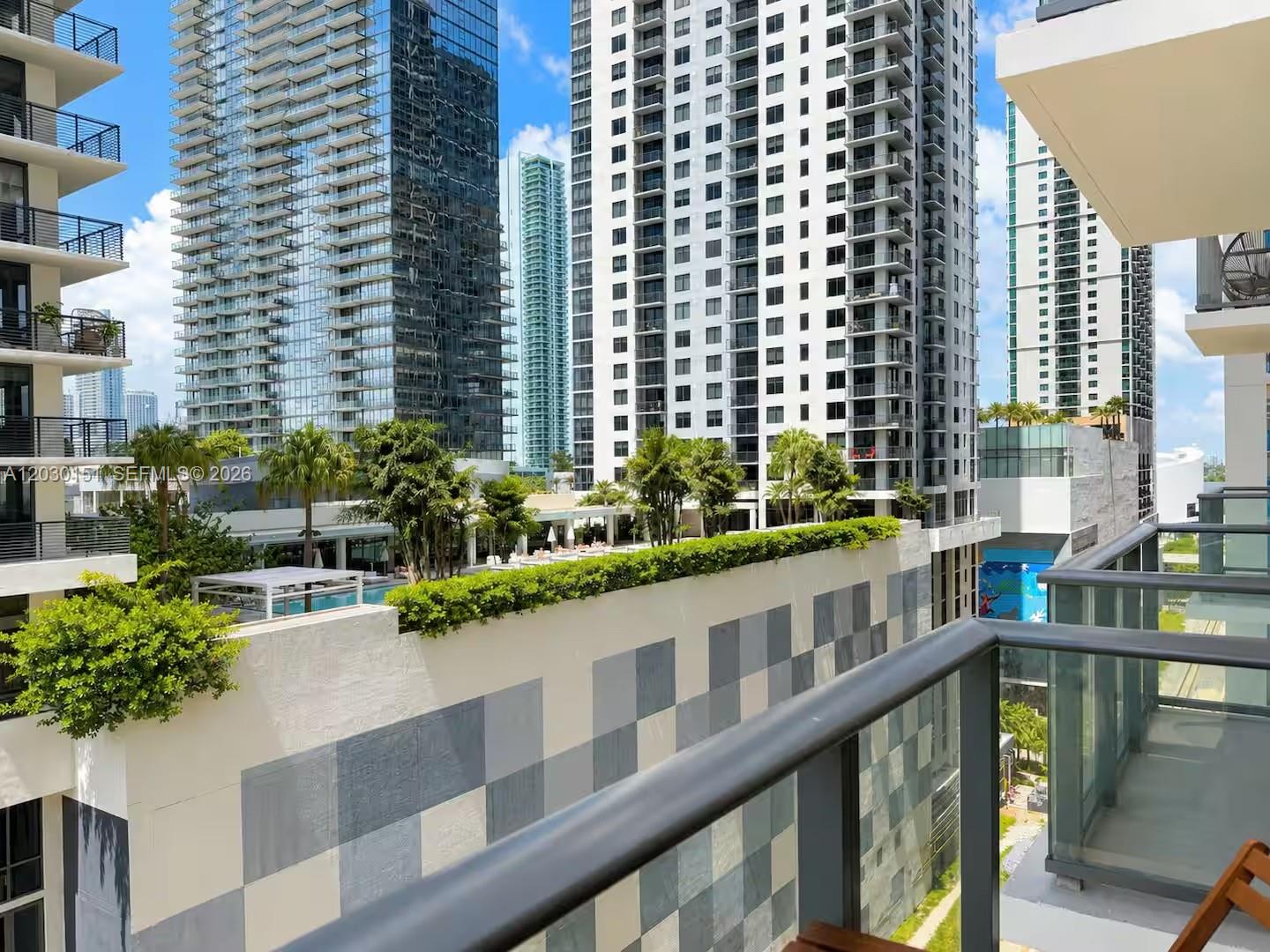 A balcony view overlooks a swimming pool deck surrounded by tall modern residential buildings — 11 NE 6th St # 1212, Miami FL 33132, MIAMI, FL
