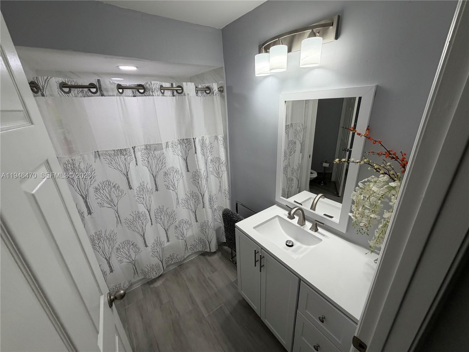 A bathroom features a white vanity, a gray-toned floor, and a tree-patterned shower curtain — 6788 Bitterbush Pl, Boynton Beach FL 33472, BOYNTON BEACH, FL