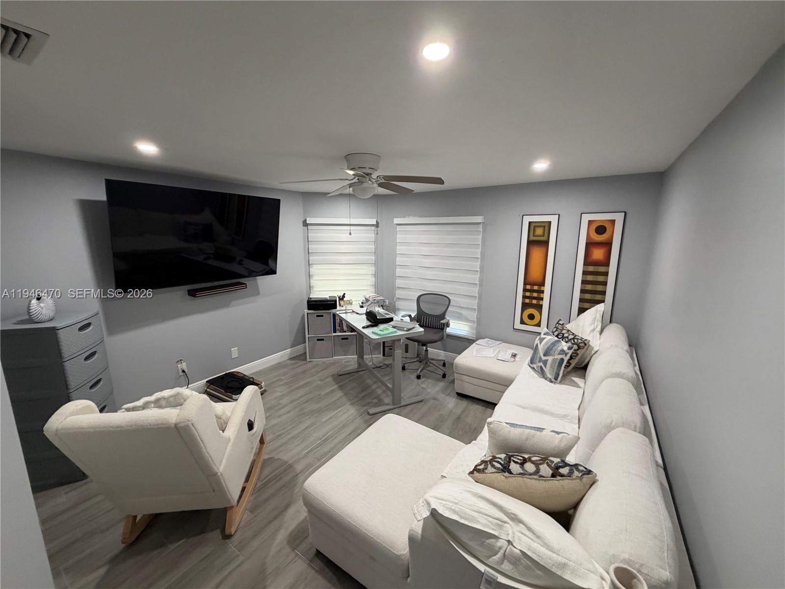 A home office features a white sectional sofa, a desk, a television, and gray flooring — 6788 Bitterbush Pl, Boynton Beach FL 33472, BOYNTON BEACH, FL