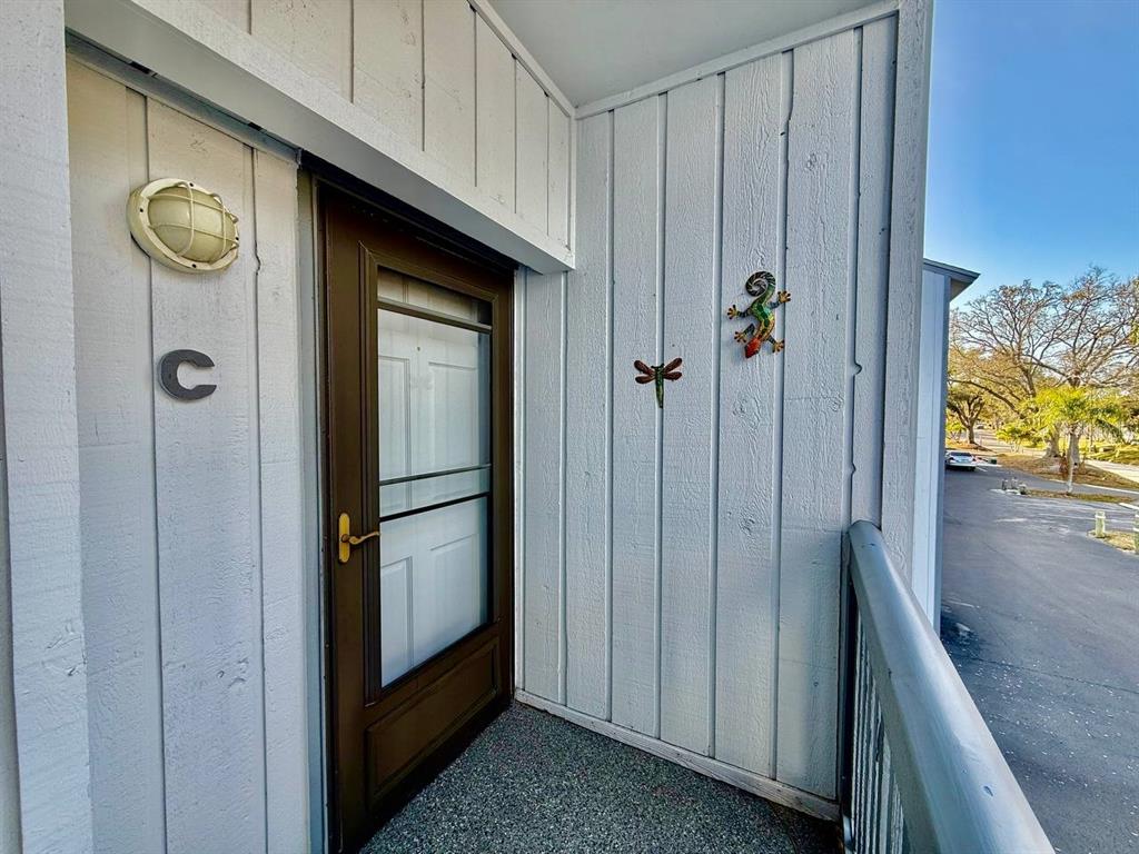 An exterior view of a building entrance with a brown door and white siding — 821 BAHIA DEL SOL DRIVE UNIT C, RUSKIN, FL
