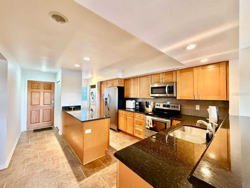 A kitchen features light wood cabinets, dark granite countertops, stainless steel appliances, and tile flooring — 821 BAHIA DEL SOL DRIVE UNIT C, RUSKIN, FL