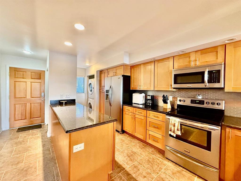 A kitchen with light wood cabinets, granite countertops, stainless steel appliances, and tile flooring — 821 BAHIA DEL SOL DRIVE UNIT C, RUSKIN, FL