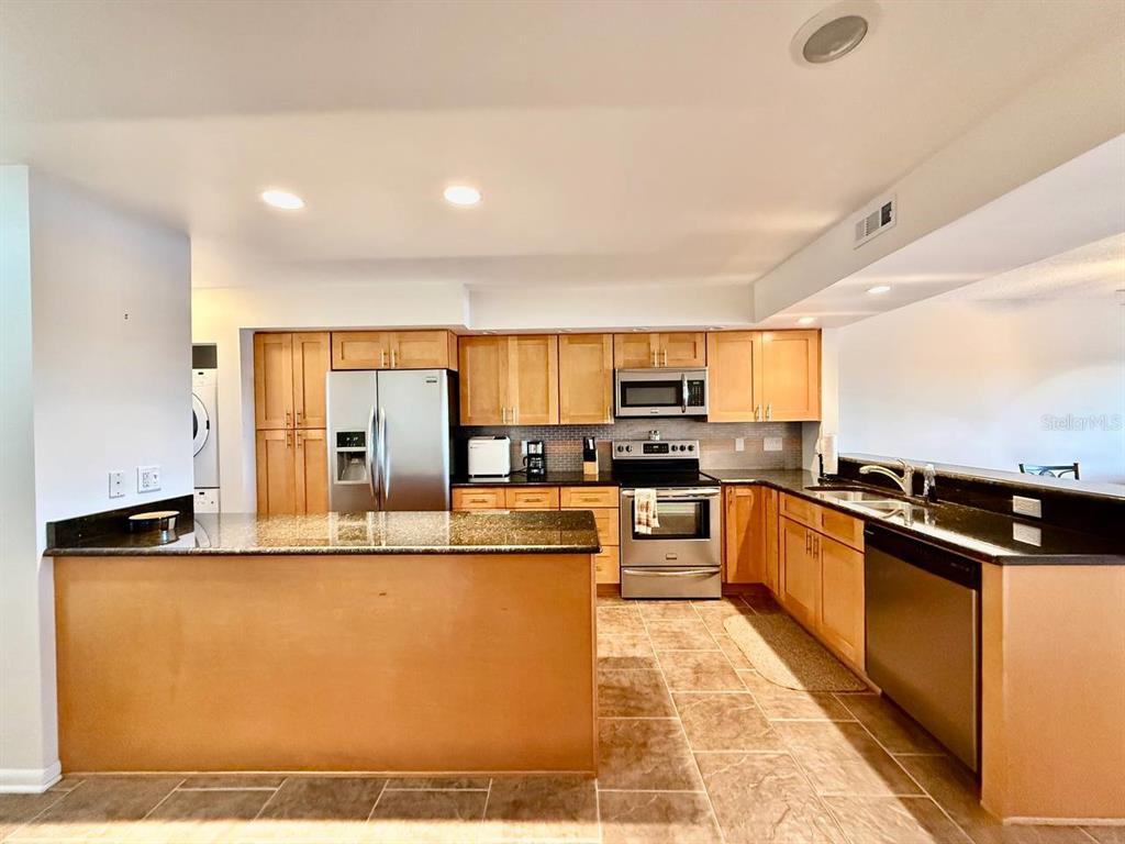 A kitchen features light wood cabinets, granite countertops, and stainless steel appliances — 821 BAHIA DEL SOL DRIVE UNIT C, RUSKIN, FL