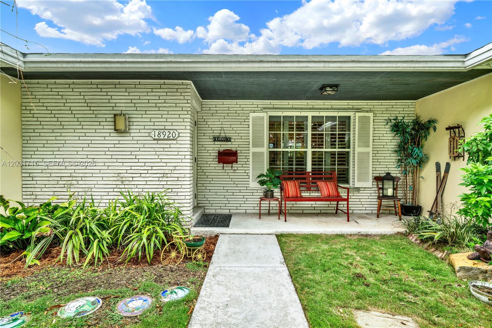 A white brick house exterior features a front porch with a red bench and walkway — 18920 SW 92nd Ct, Cutler Bay FL 33157, CUTLER BAY, FL
