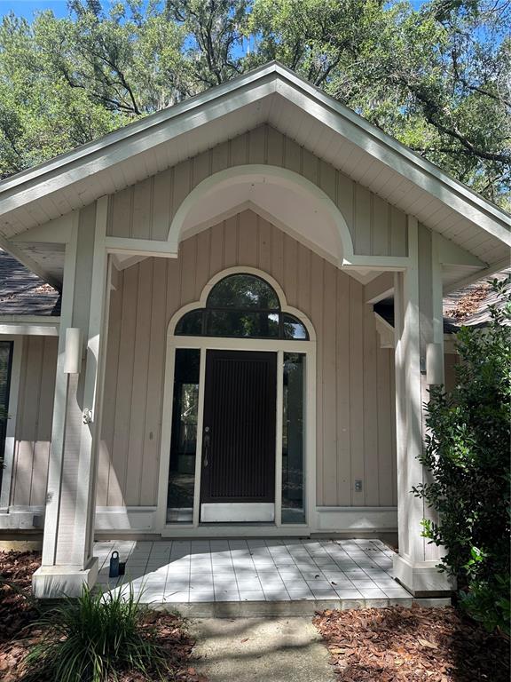 The exterior of a house features a covered entryway with a dark door and columns — 4722 SW 88TH DRIVE, GAINESVILLE, FL