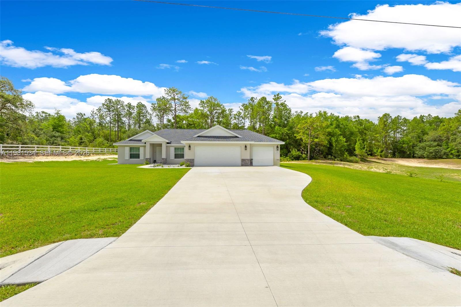 A single-story house with a three-car garage sits on a large, grassy lot — 13822 SW 61 Pl Rd, Ocala FL 34481, OCALA, FL