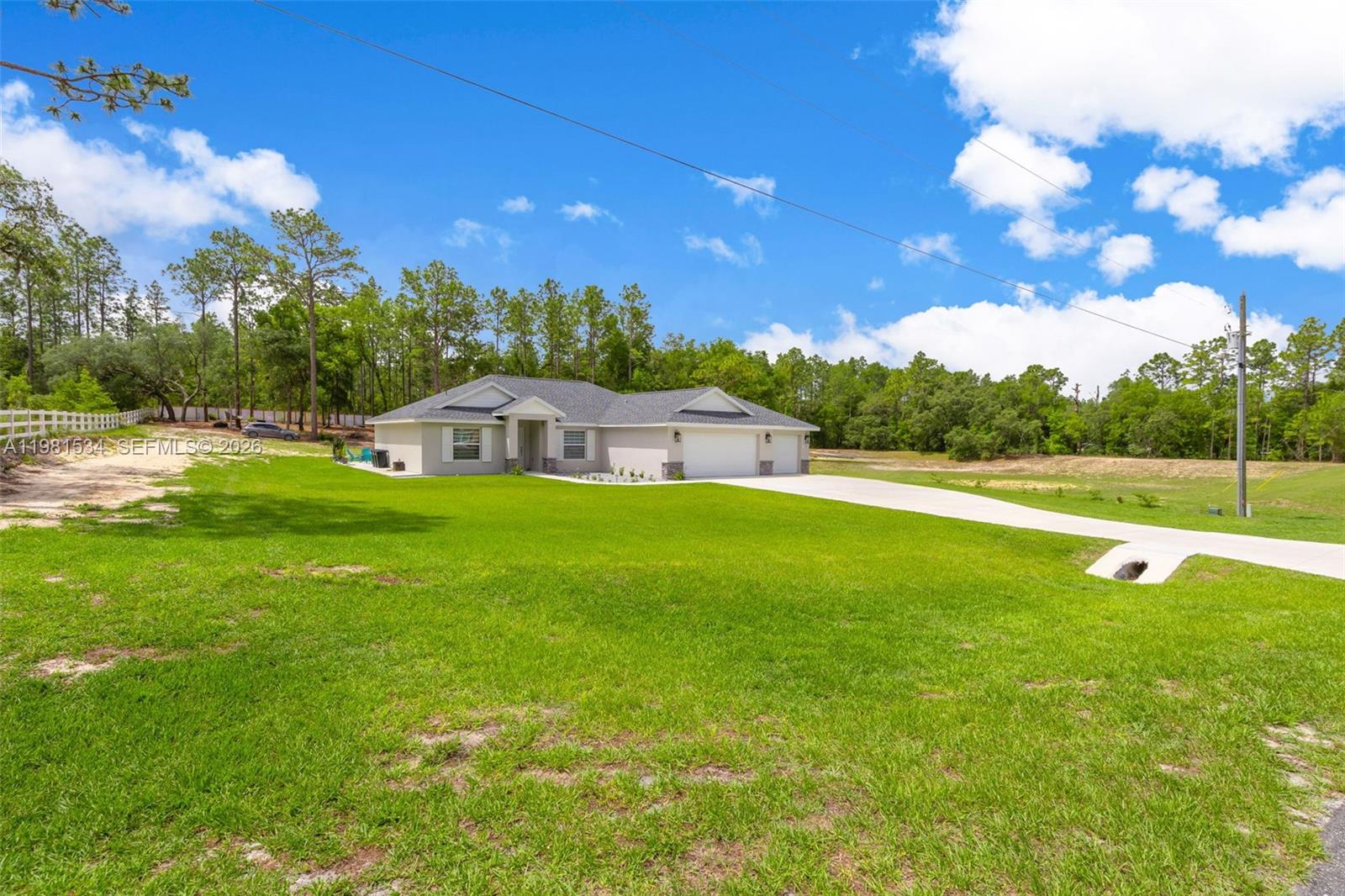 A single-story house with a two-car garage sits on a large, grassy lot — 13822 SW 61 Pl Rd, Ocala FL 34481, OCALA, FL