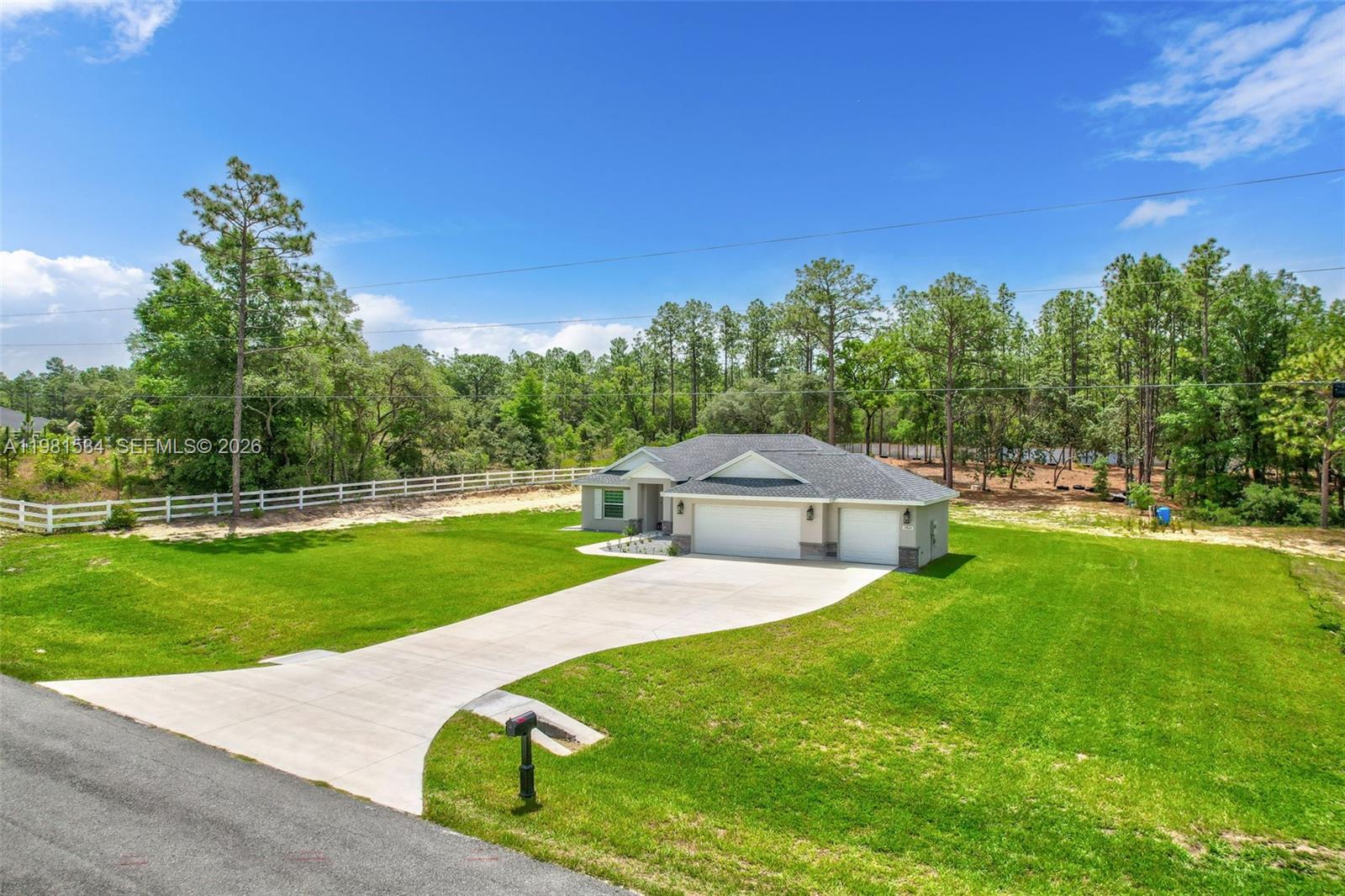 A single-story house with a three-car garage sits on a large, grassy lot — 13822 SW 61 Pl Rd, Ocala FL 34481, OCALA, FL