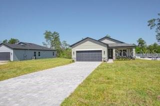 A single-story house with a gray garage and a paved driveway sits on a grassy lot — 602 MARION OAKS LANE, OCALA, FL