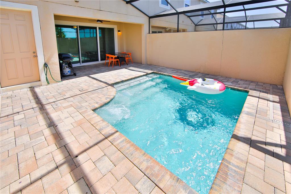 A small rectangular swimming pool sits on a paved patio enclosed by a screen cage — 1515 CAREY PALM CIRCLE, KISSIMMEE, FL