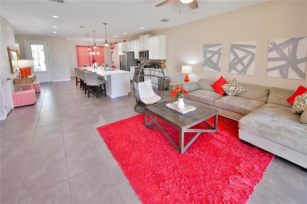 An open-concept living room and kitchen feature a bright red rug and tile flooring — 1515 CAREY PALM CIRCLE, KISSIMMEE, FL