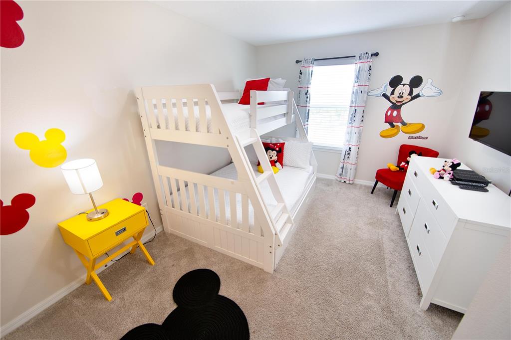 A bedroom features a white bunk bed, a yellow nightstand, and Mickey Mouse-themed wall decor — 1515 CAREY PALM CIRCLE, KISSIMMEE, FL