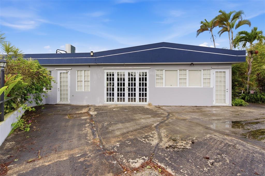 The exterior of a single-story gray building features a blue roofline and a concrete driveway — carr. 739, km. 3.4 CAMINO MONTICELLO, CIDRA, PR