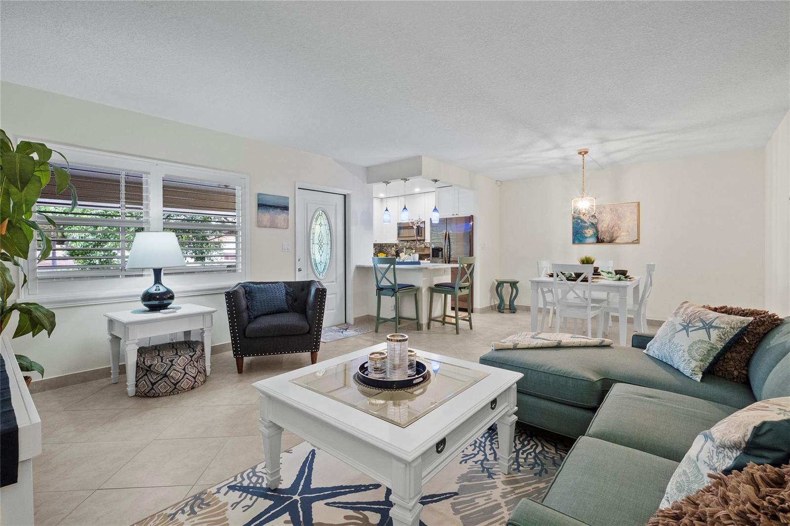 A bright living and dining area features tile floors, a sectional sofa, and kitchen seating — 1340 NE 28th Avenue # 242, Pompano Beach FL 33062, POMPANO BEACH, FL