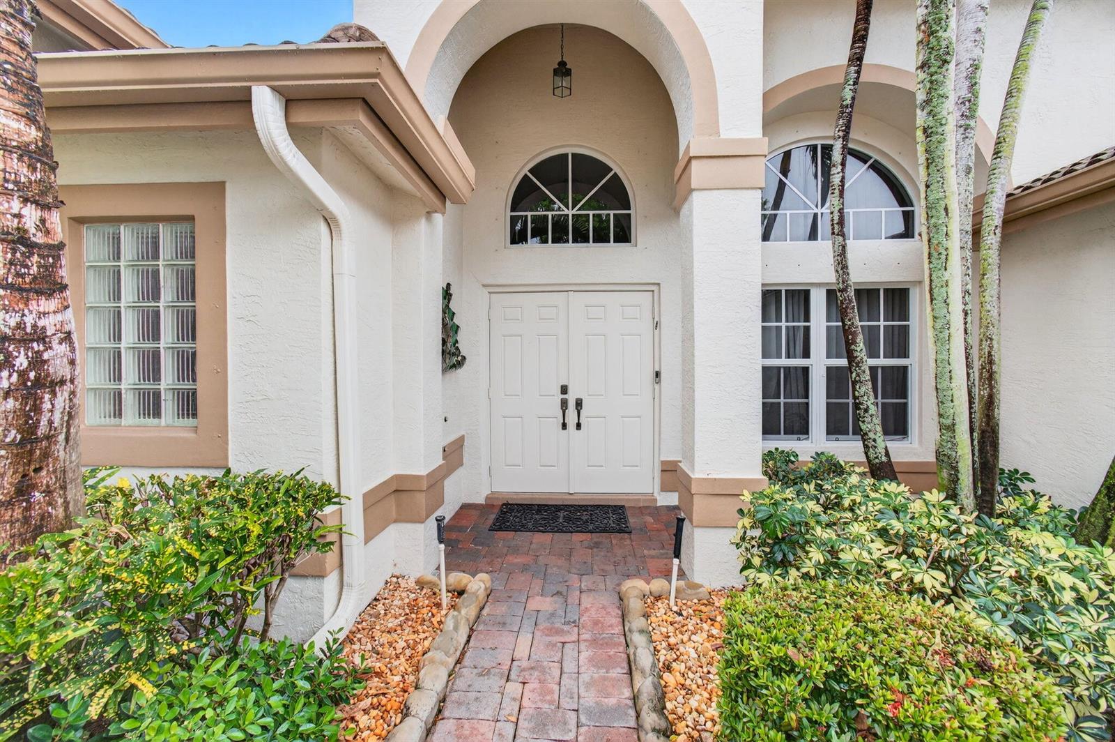 The exterior of a house features a double front door under an arched entryway — 11511 Pamplona Boulevard, Boynton Beach FL 33437, BOYNTON BEACH, FL
