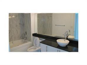 A bathroom features a marble-tiled bathtub, a white toilet, and a vanity with a vessel sink — 31 SE 5th Street # 3207, Miami FL 33131, MIAMI, FL