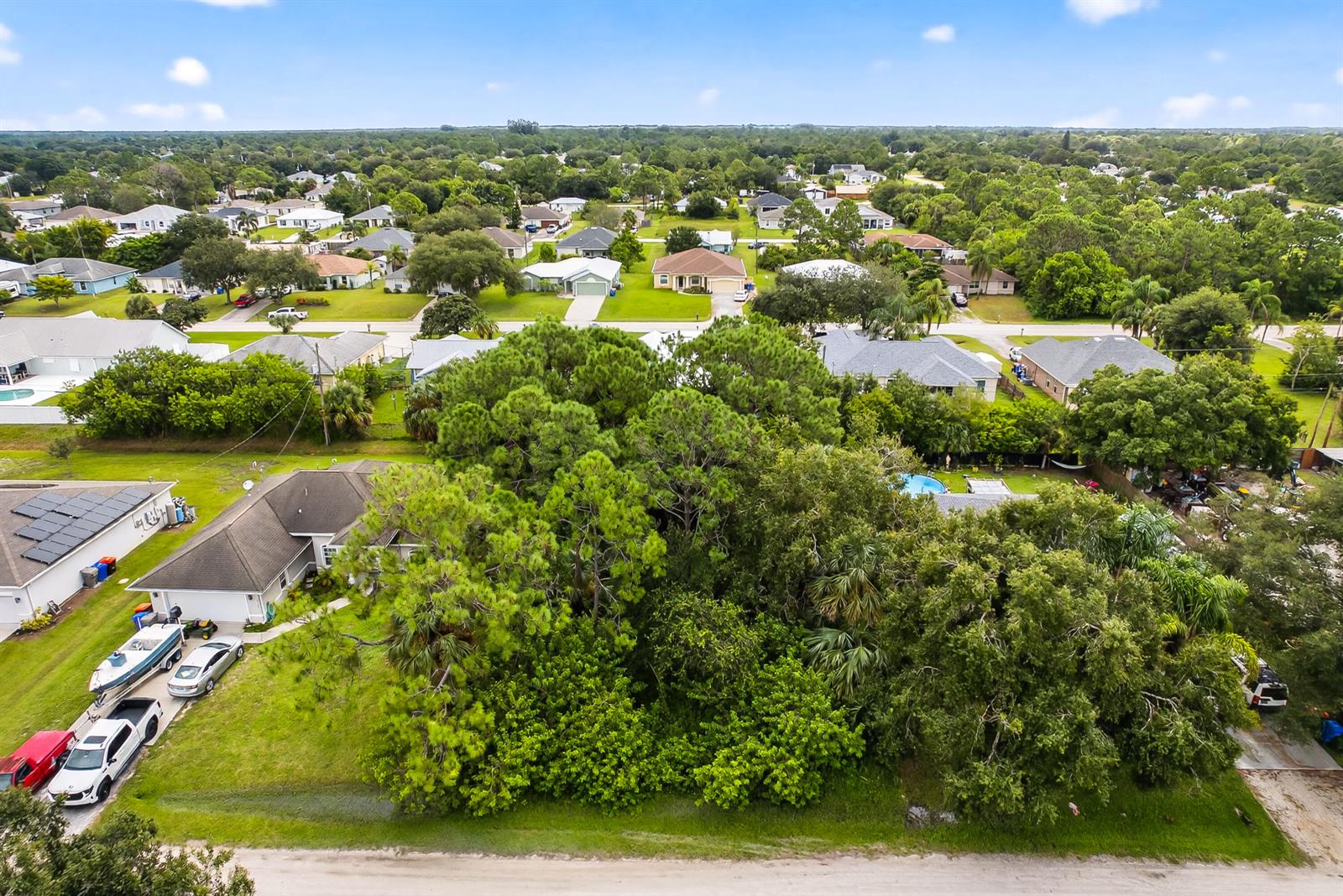 An aerial view shows a residential neighborhood with houses, dense trees, and parked vehicles — 8156 101st Court, Vero Beach FL 32967, VERO BEACH, FL