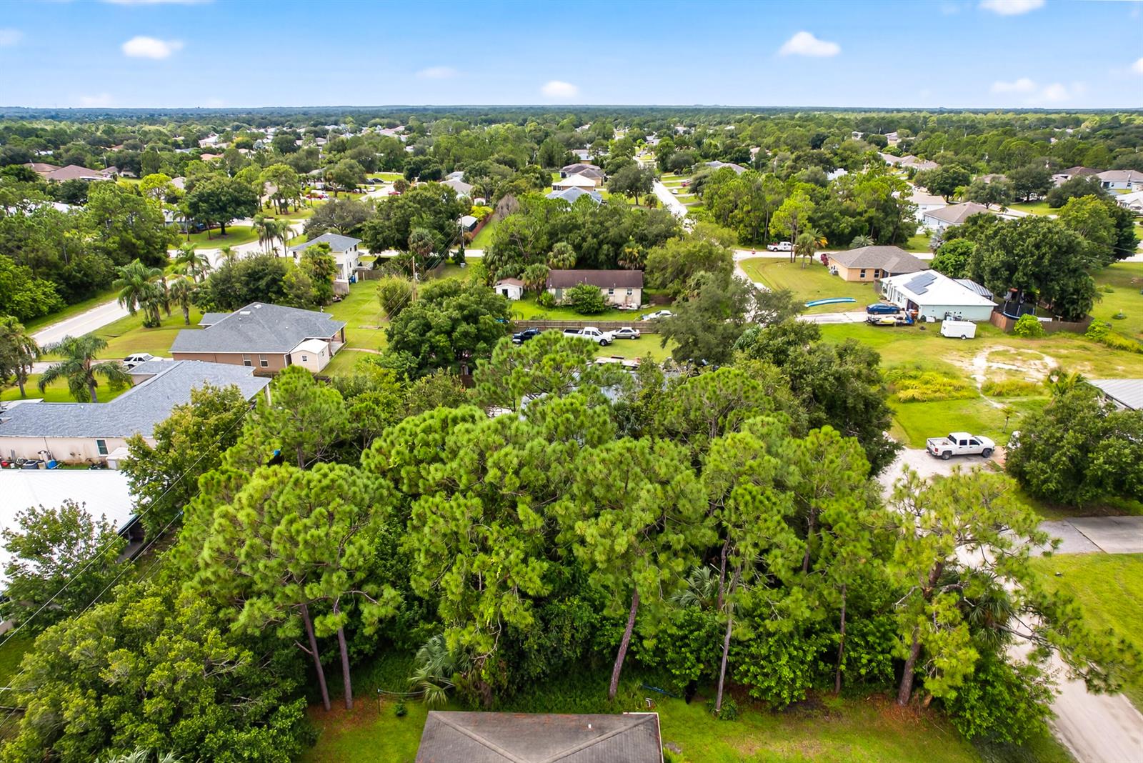 An aerial view shows a residential neighborhood with houses surrounded by dense trees and greenery — 8156 101st Court, Vero Beach FL 32967, VERO BEACH, FL