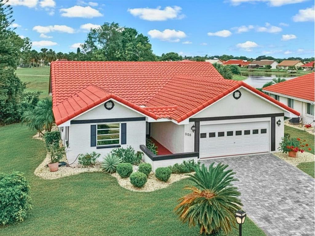 A single-story house with a white exterior, red tile roof, and a paved driveway — 705 WESTMONT WAY, SUN CITY CENTER, FL