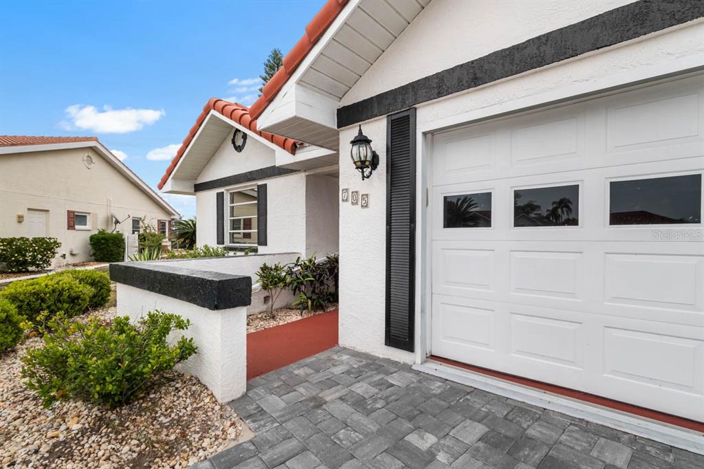The exterior of a white house features a garage, a tiled roof, and a walkway — 705 WESTMONT WAY, SUN CITY CENTER, FL