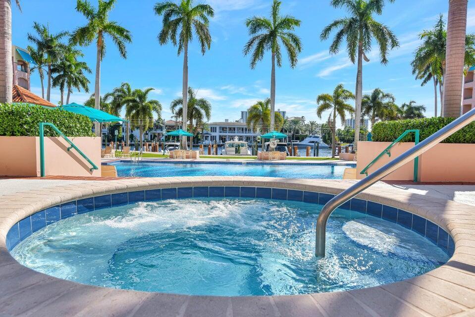 A hot tub in the foreground overlooks a swimming pool, palm trees, and a marina — 100 SE 5th Avenue # 107, Boca Raton FL 33432, BOCA RATON, FL