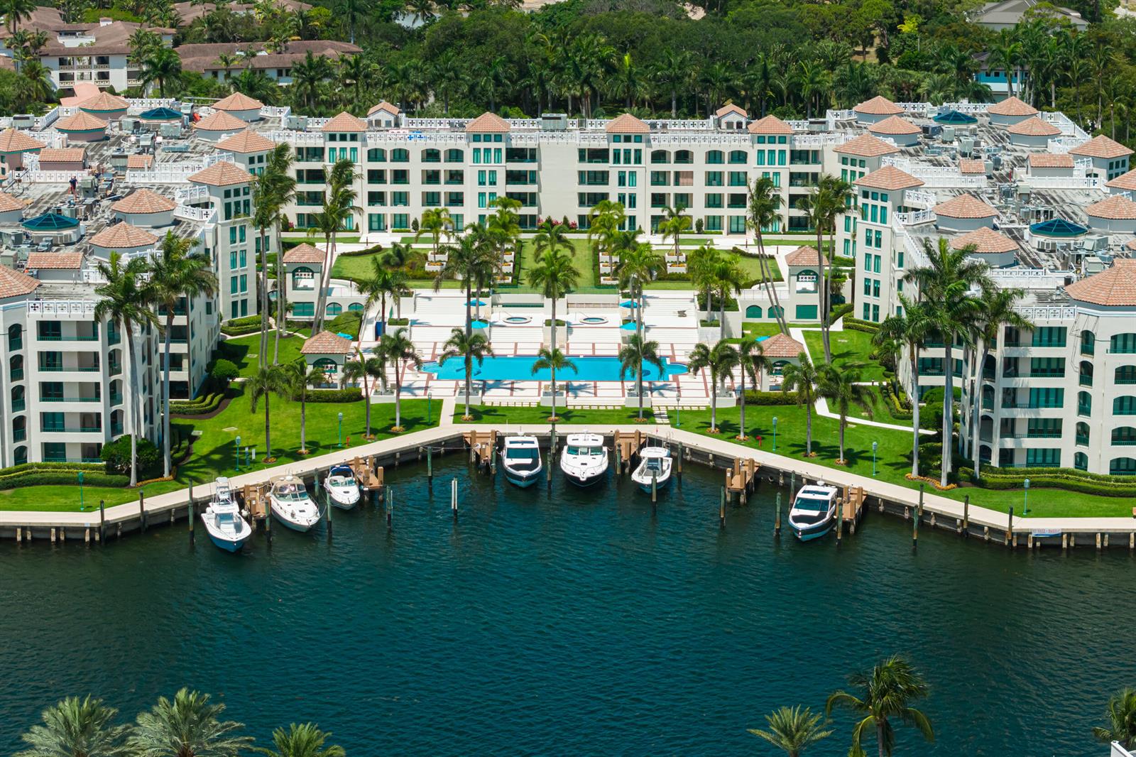 An aerial view shows a large multi-story apartment complex with a pool and private boat docks — 100 SE 5th Avenue # 107, Boca Raton FL 33432, BOCA RATON, FL