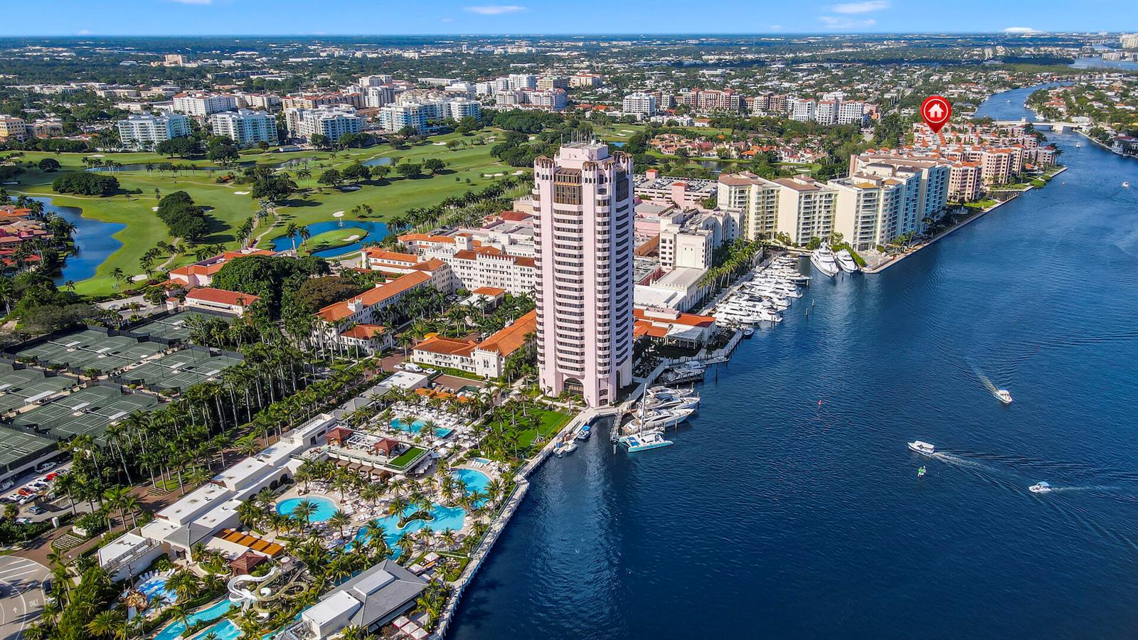 Aerial view of a tall pink hotel, marina, swimming pools, and tennis courts near water — 100 SE 5th Avenue # 107, Boca Raton FL 33432, BOCA RATON, FL
