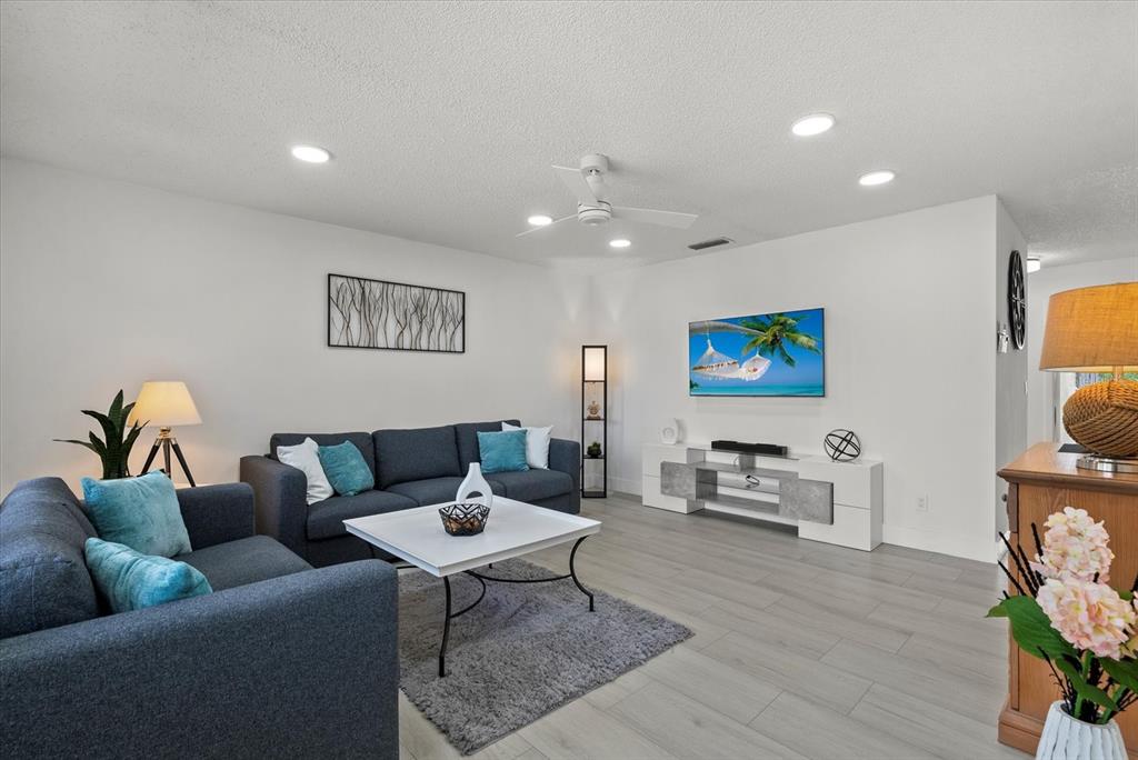 A living room features gray sofas, a white coffee table, and a wall-mounted television — 22375 EDGEWATER DRIVE UNIT 241, PORT CHARLOTTE, FL