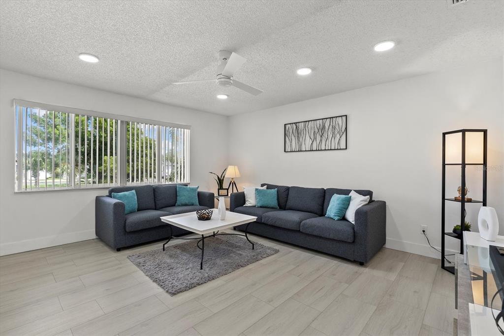 A living room features two dark gray sofas, a white coffee table, and light wood-look flooring — 22375 EDGEWATER DRIVE UNIT 241, PORT CHARLOTTE, FL