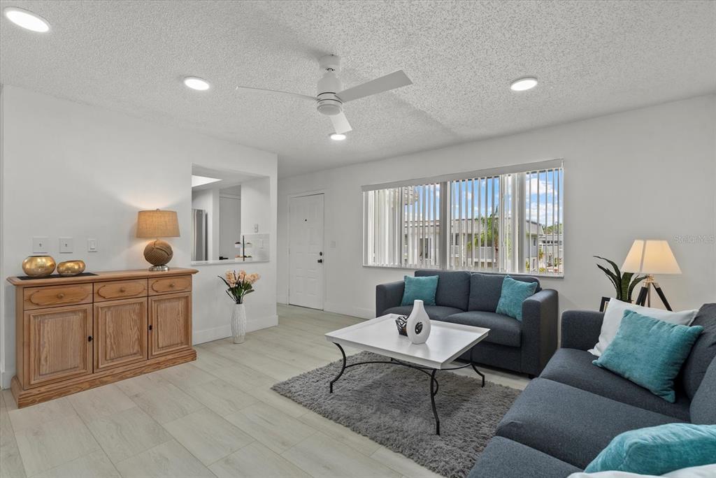 A living room features light wood-look flooring, a gray sofa, and a wooden sideboard — 22375 EDGEWATER DRIVE UNIT 241, PORT CHARLOTTE, FL