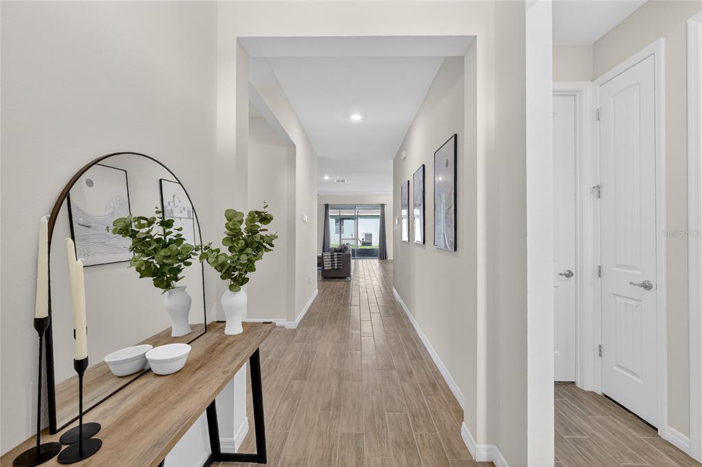 A hallway with wood-look tile flooring leads toward a living area with a glass door — 1558 TISBURY PT, SANFORD, FL