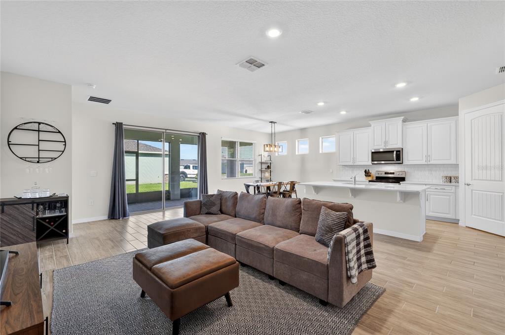 An open-concept living room and kitchen featuring a large sectional sofa and tile flooring — 1558 TISBURY PT, SANFORD, FL