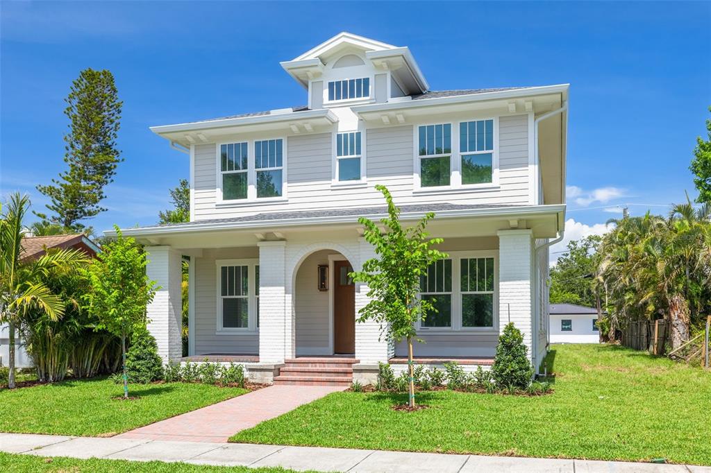 A two-story house with light gray siding, a white brick porch, and a front lawn — 2011 10TH STREET N, ST PETERSBURG, FL
