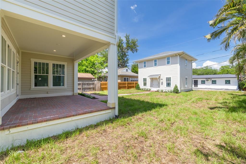 A covered brick patio overlooks a backyard with a two-story house and a detached garage — 2011 10TH STREET N, ST PETERSBURG, FL
