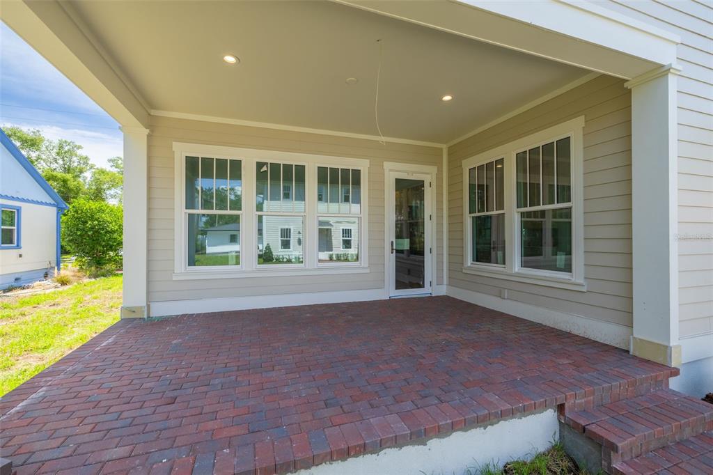 A covered brick patio features light-colored siding, multiple windows, and a glass-paneled door — 2011 10TH STREET N, ST PETERSBURG, FL