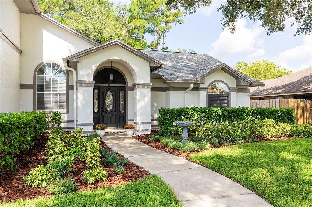 A concrete walkway leads to the arched front entrance of a single-story stucco home — 804 SILVERWOOD DRIVE, LAKE MARY, FL