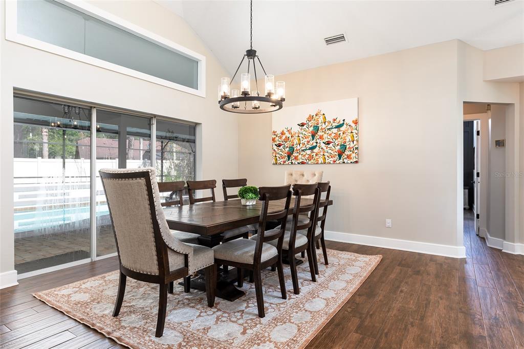 A dining room features a wooden table, upholstered chairs, a chandelier, and a large painting — 804 SILVERWOOD DRIVE, LAKE MARY, FL
