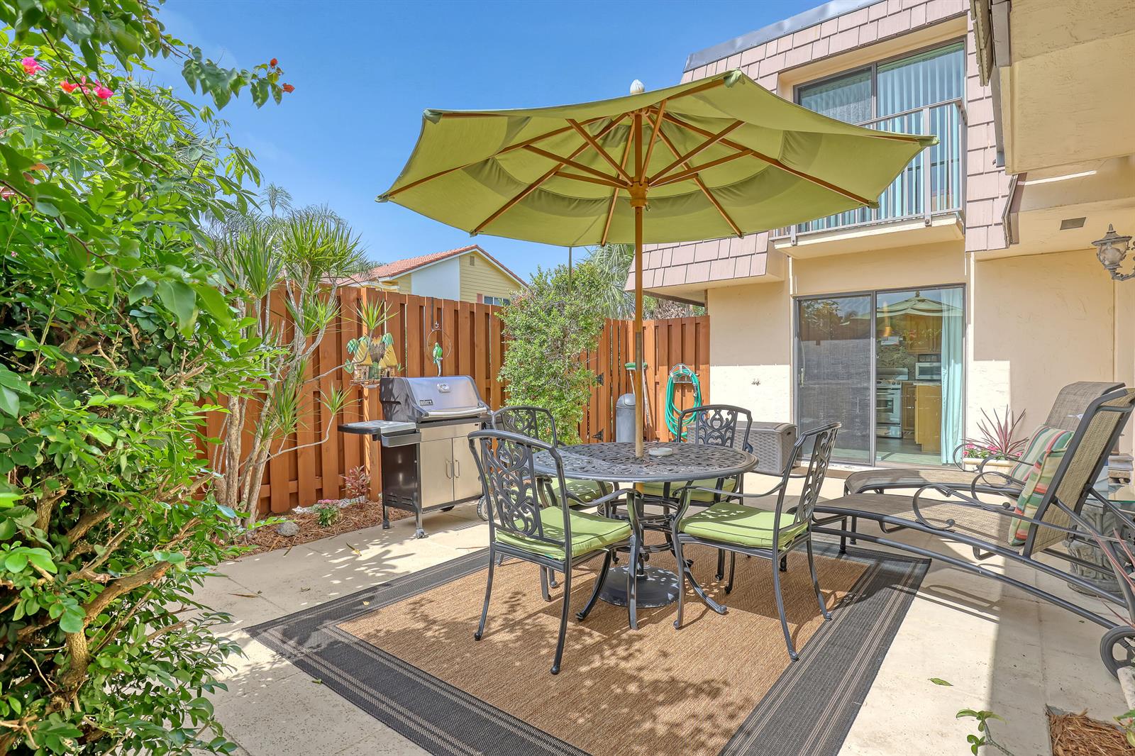 A patio features a dining set with a green umbrella, a grill, and lounge chairs — 131 Ocean Cove Drive, Jupiter FL 33477, JUPITER, FL