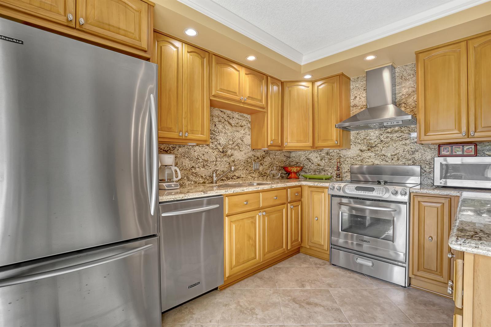 A kitchen features light wood cabinets, stainless steel appliances, and granite countertops — 131 Ocean Cove Drive, Jupiter FL 33477, JUPITER, FL