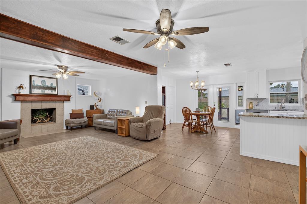 An open-concept living and dining area features tile flooring, a fireplace, and a ceiling fan — 5010 STOLLS AVENUE, TAMPA, FL