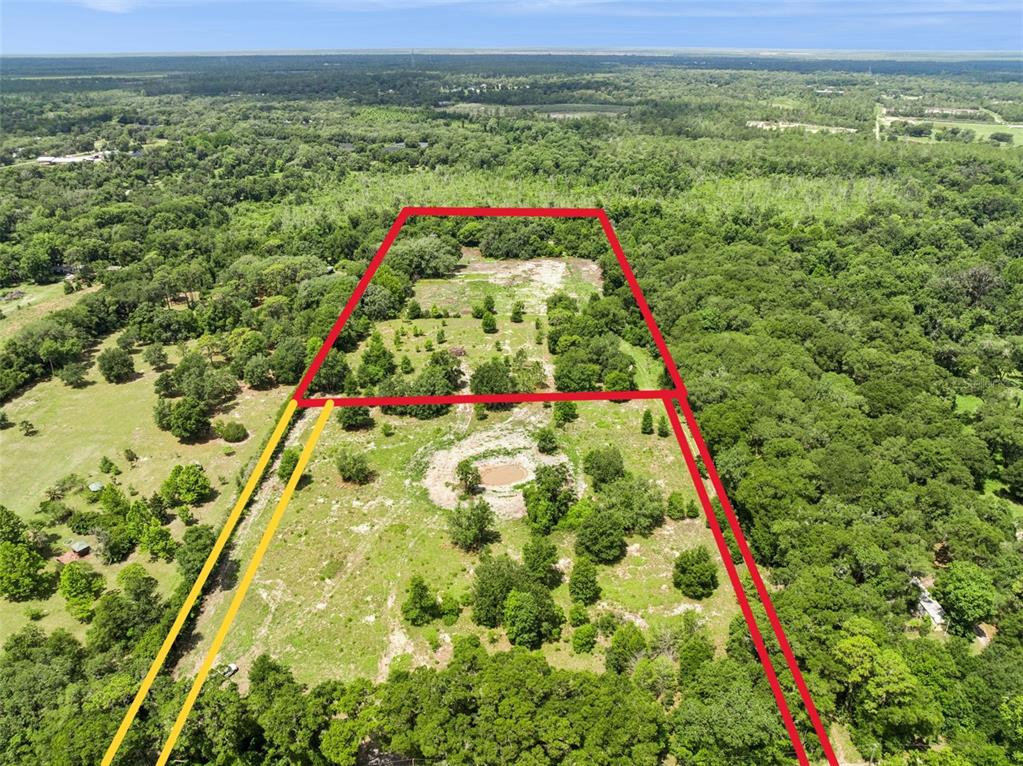 An aerial view shows a large, partially wooded plot of land marked with red lines — 2040 HOLLY HAMMOCK ROAD, DE LEON SPRINGS, FL