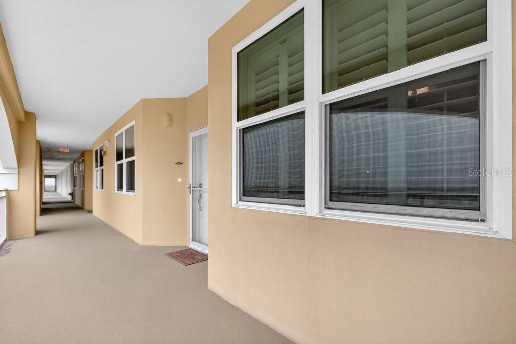 A beige exterior hallway features a white door, windows with shutters, and a concrete floor — 80 SURFVIEW DRIVE UNIT 707, PALM COAST, FL