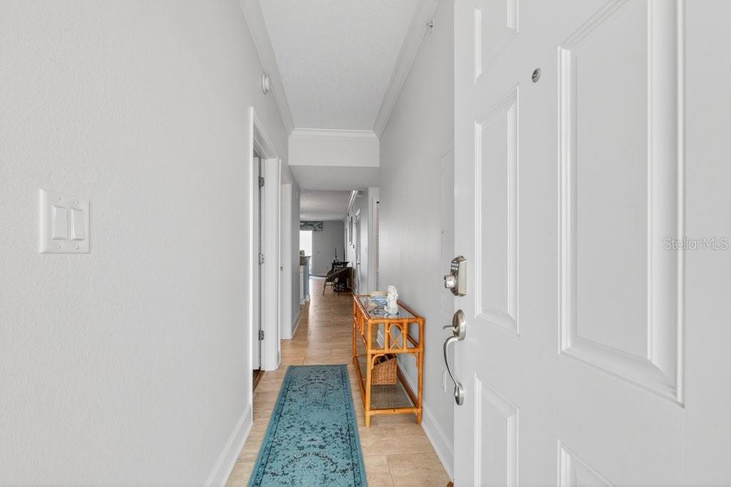 A view from an open white door into a hallway with tile flooring and furniture — 80 SURFVIEW DRIVE UNIT 707, PALM COAST, FL