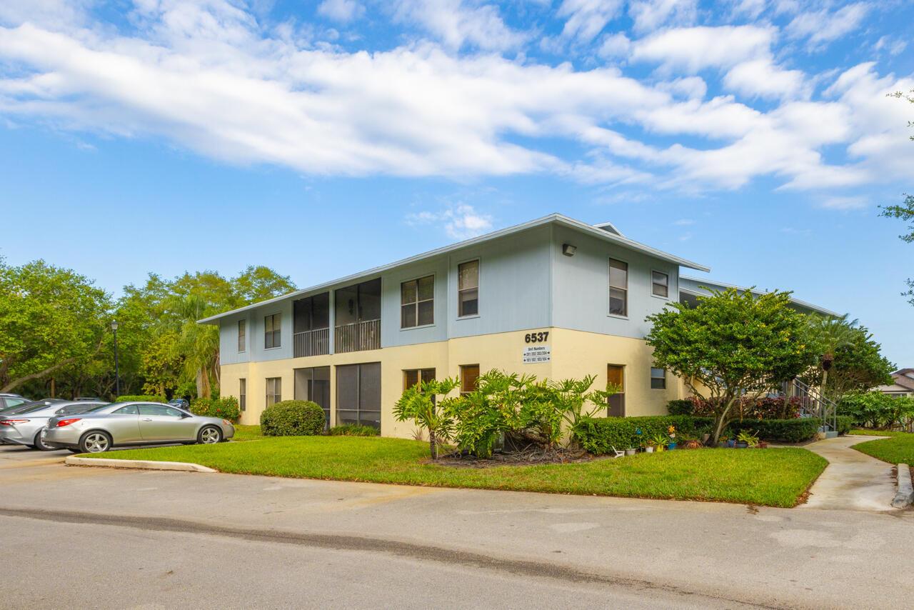 A two-story apartment building with light blue and yellow siding sits under a blue sky — 6537 SE Federal Highway # 101, Stuart FL 34997, STUART, FL