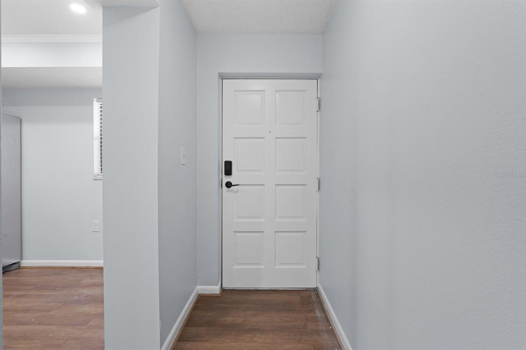 An entryway features a white front door, light gray walls, and wood-look flooring — 2650 COUNTRYSIDE BOULEVARD UNIT B307, CLEARWATER, FL