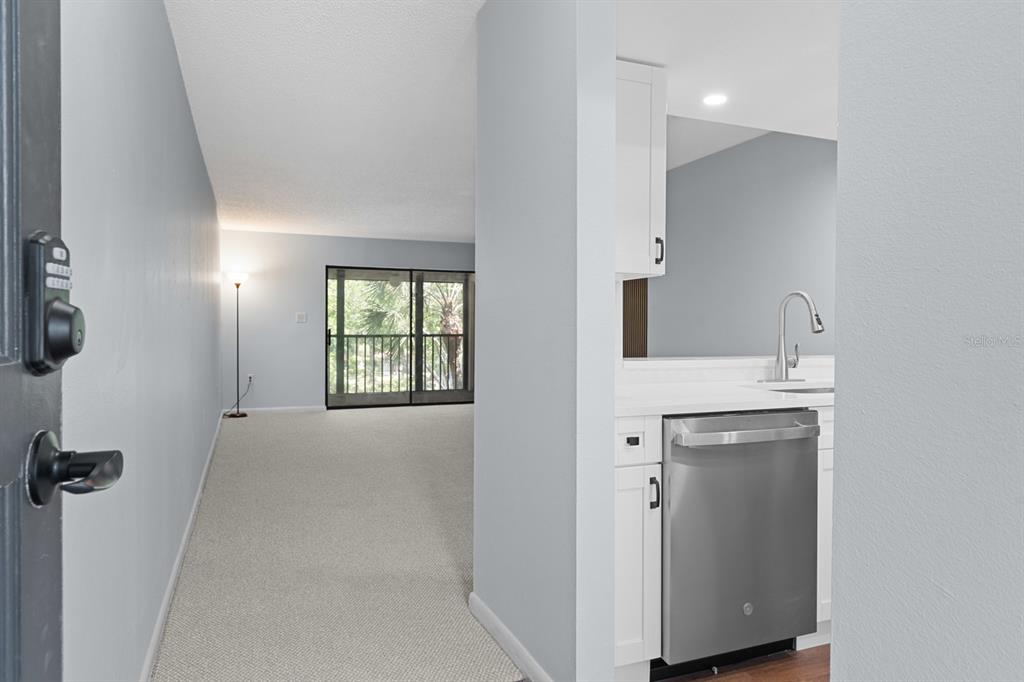 A view from a doorway looking into a carpeted living area and a modern kitchen — 2650 COUNTRYSIDE BOULEVARD UNIT B307, CLEARWATER, FL