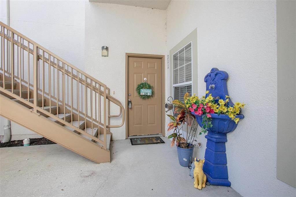 An exterior entryway features a tan door, a metal staircase, and a blue decorative fountain — 970 N SPRING GARDEN AVENUE UNIT 311, DELAND, FL